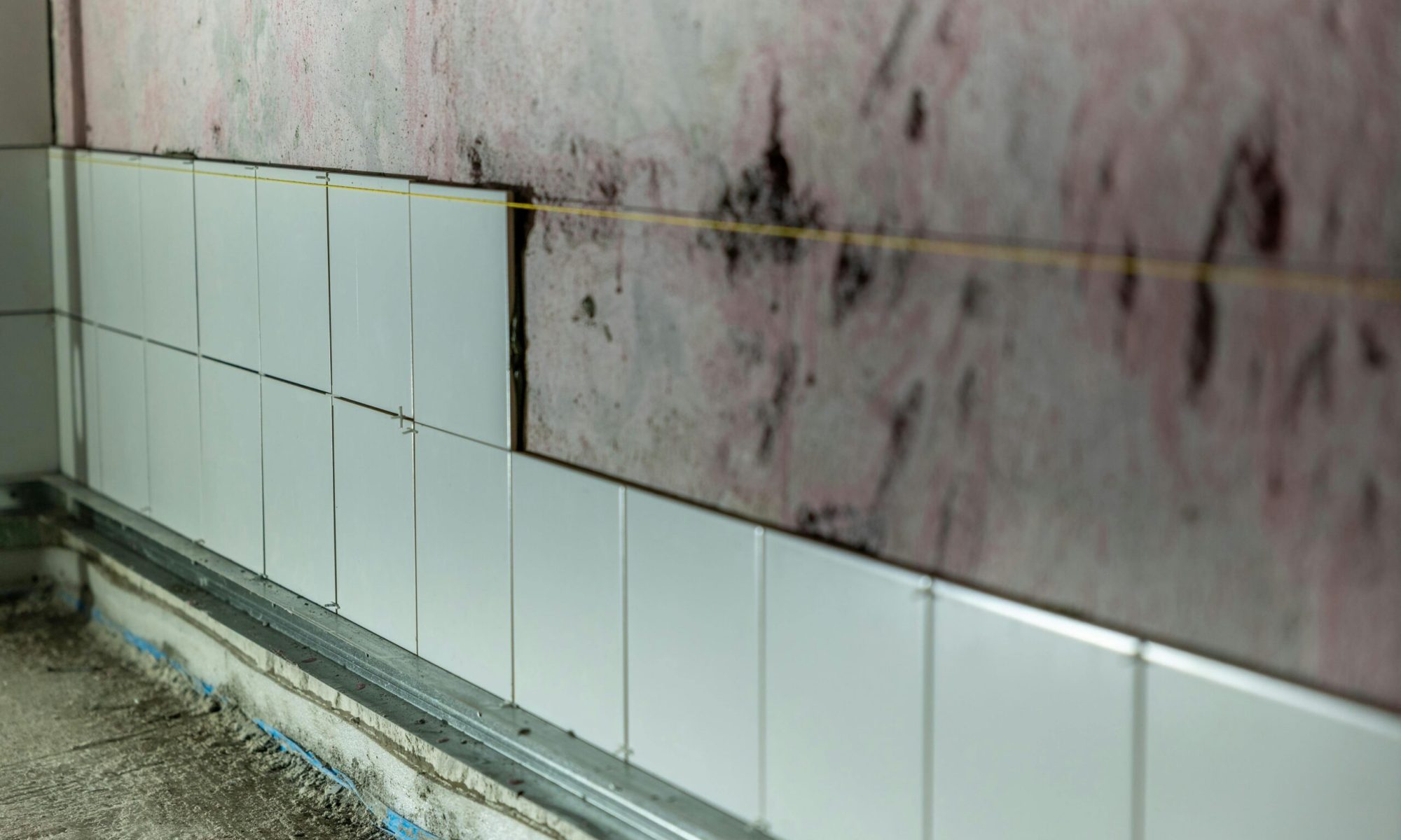 Close-up of partially tiled wall in a construction area, showcasing incomplete renovation work.